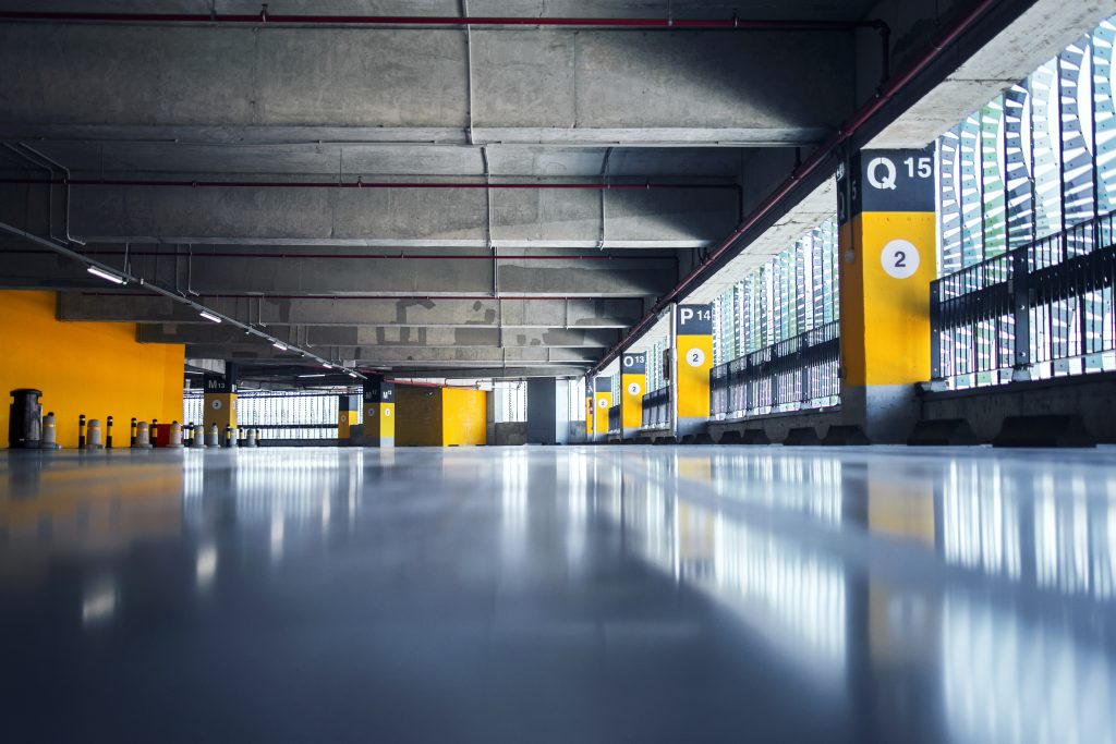 Empty garage with parking lots with concrete ceiling and flooring and pillars marked with numbers.